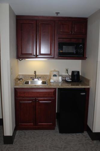 a small kitchen with wooden cabinets and a sink at Wingate by Wyndham Columbia/Lexington in Lexington