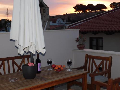 Onar Superior Suites في مدينة ريثيمنو: طاولة مع مظلة وكأسين من النبيذ