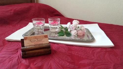 a tray with glasses and a plate with flowers on a bed at Mprizis Rooms in Elati Trikalon