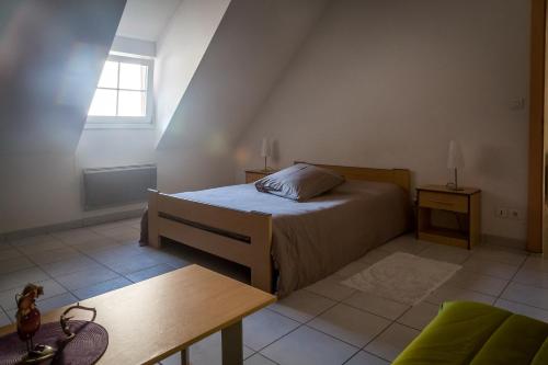 een slaapkamer met een bed, een tafel en een raam bij Gîtes & Chambes d'Hôtes Fugler in Orschwihr