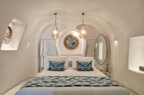 ein weißes Zimmer mit einem Bett mit blauen und weißen Kissen in der Unterkunft Limestone in Fira