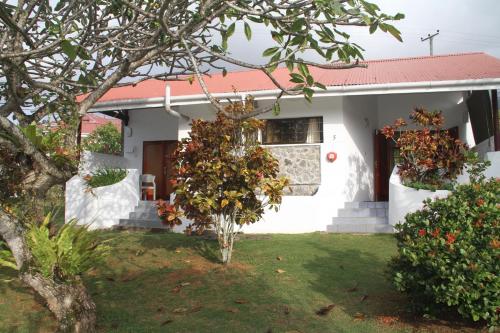 a white house with a tree in the yard at Daniella's Bungalows in Bel Ombre