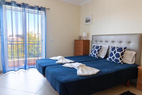 a bedroom with a bed with blue sheets and a large window at Penthouse Cabanas Sun - Algarve in Cabanas de Tavira