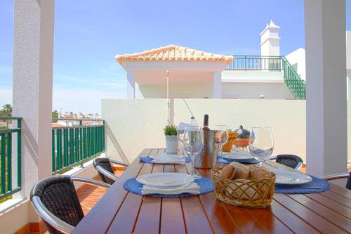 a wooden table with plates and wine glasses on a balcony at Penthouse Cabanas Sun - Algarve in Cabanas de Tavira