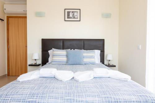 a large bed with a blue and white comforter and two lamps at Penthouse Cabanas Sun - Algarve in Cabanas de Tavira