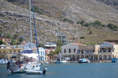 a sailboat is docked in a harbor with houses at Royal Villa Pedi in Symi