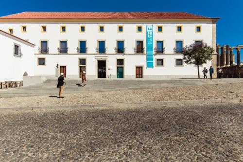 a man standing in front of a white building at Heaven Inn Suites & Terrace in Évora