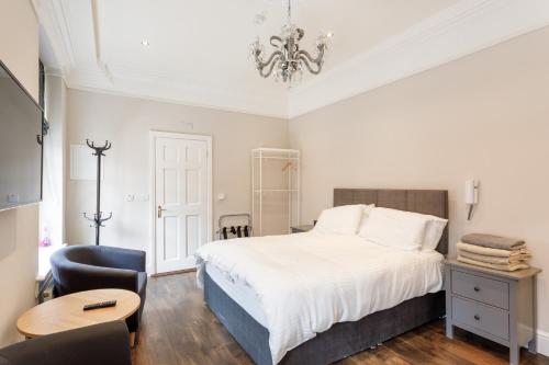 a bedroom with a bed and a chair and a chandelier at Molloys Apartments in Dublin