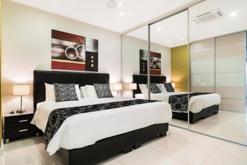 a bedroom with two beds and a mirror at Elsey on Parap in Darwin