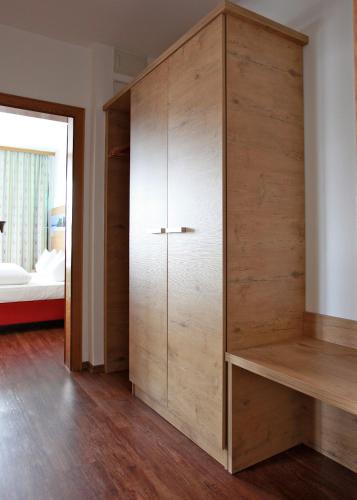 a large wooden cabinet in a room with a bed at Gasthof-Hotel Höhensteiger in Rosenheim
