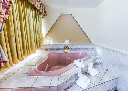 y baño con bañera rosa y techo. en Vagabond Inn Long Beach, en Long Beach