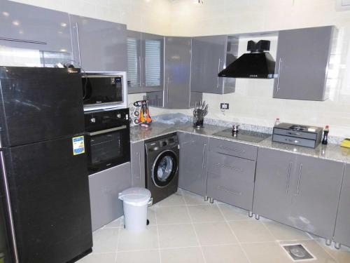eine Küche mit einem schwarzen Kühlschrank und einem Geschirrspüler in der Unterkunft Three-Bedroom Apartment at Louly Beach Resort in Ain Suchna