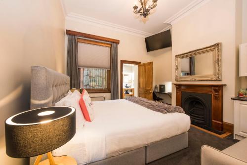 a bedroom with a bed and a chair and a fireplace at The Parkview Hotel Mudgee in Mudgee