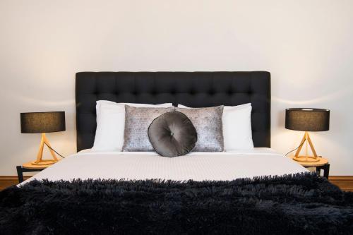 a bedroom with a bed with a black headboard and two lamps at The Parkview Hotel Mudgee in Mudgee