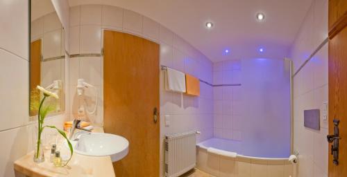 a bathroom with a sink and a bath tub at Landhotel Huberhof in Schwangau