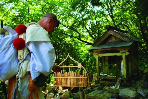 a man standing next to a small bird cage at Kumano Backpackers in Tanabe