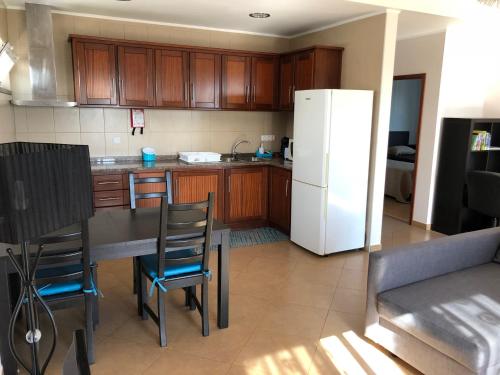 a kitchen with a table and a white refrigerator at casa da rochinha in Lajes do Pico