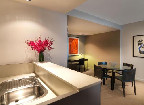 a kitchen and dining room with a sink and a table at Adina Apartment Hotel Sydney, Darling Harbour in Sydney