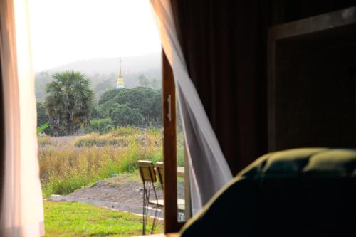 a room with a window with a view of a field at Suan Sook Homestay in Chom Thong