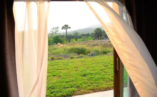 a window with a view of a field of grass at Suan Sook Homestay in Chom Thong