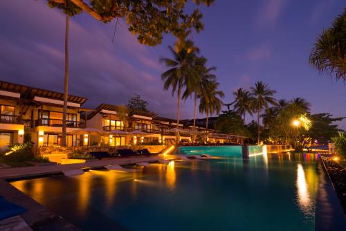 a resort pool at night with palm trees and buildings at Katamaran Hotel & Resort in Senggigi 