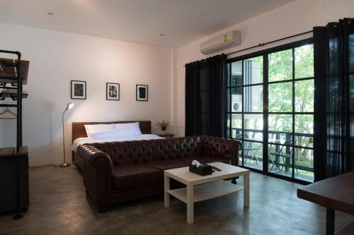 a living room with a couch and a large window at Photharam126 Resort in Ban Khlong Ta Khot