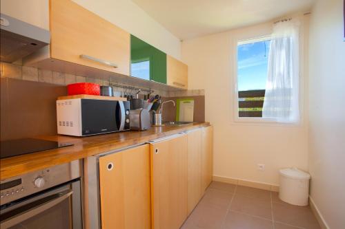a kitchen with a counter with a microwave and a window at Residence Agula Mora in Lecci
