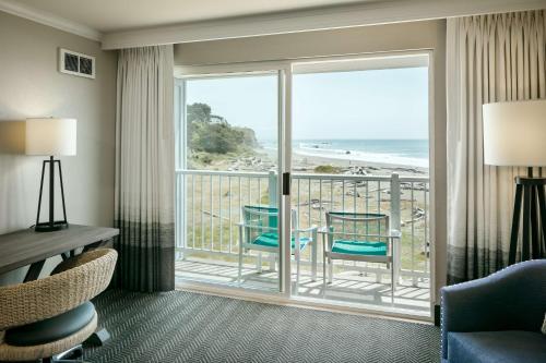 a room with a balcony with a view of the beach at Beachfront Inn in Brookings