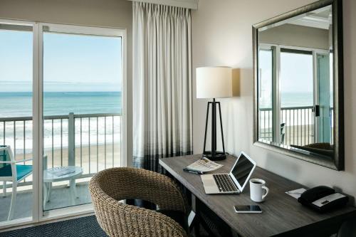 a room with a desk with a laptop and a balcony at Beachfront Inn in Brookings