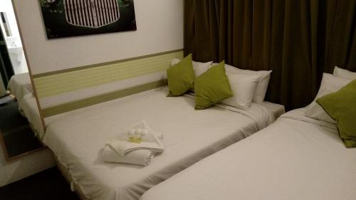 2 Betten in einem Hotelzimmer mit Handtüchern darauf in der Unterkunft Olive Hotel in Johor Bahru