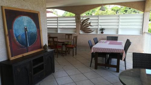 a dining room with a table and chairs and a tv at La Villa Pitaya in LʼEntre-Deux