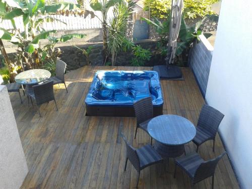 un patio con mesas y sillas y una bañera de hidromasaje. en La Villa Pitaya en LʼEntre-Deux