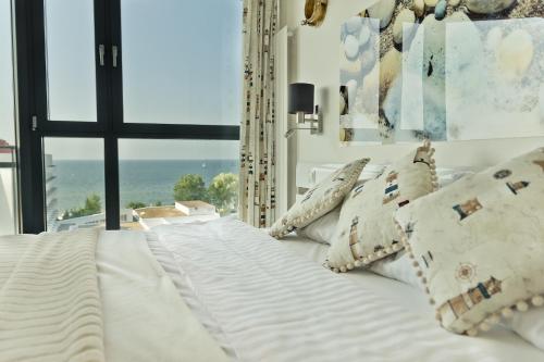 a white bed with pillows in a room with a window at Apartamenty Horyzont SeaView by Rent like home in Międzyzdroje