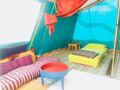 een kamer met een bank en een bed in een tent bij Gite Le Nomade in Mirleft