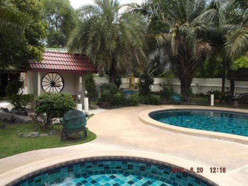 a swimming pool in front of a house with palm trees at Ryans Resort in Prasat