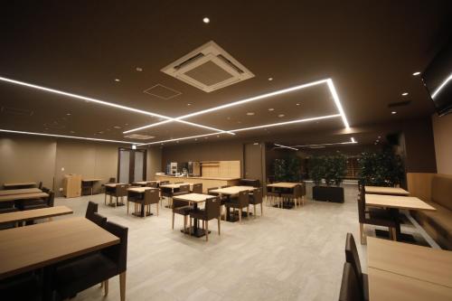 un comedor con mesas, sillas y luces en Dormy Inn Korakuen, en Tokio