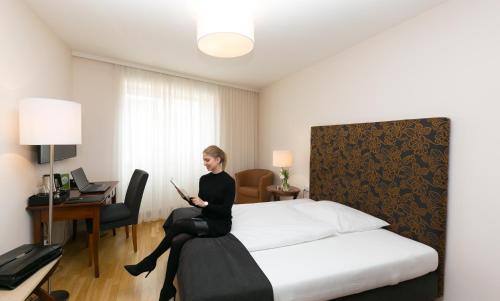 a woman sitting on a bed in a hotel room at Stadthotel zur goldenen Krone in Weiz