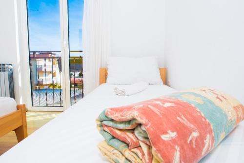 a bedroom with a white bed and a large window at Apartmani Šutić in Promajna