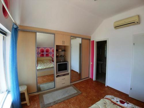 a living room with a television and a room with a bed at Котеджі на приватному пляжу - Совіньйон 2025 in Odesa