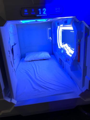 a small bed in a room with blue lights at TBS Rest & Go Transit Motel in Kuala Lumpur