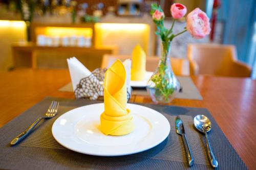 a table with a white plate with a yellow napkinweredasteryasteryasteryastery at Metropolo Shenyang Wanda Plaza-Beiyi Road in Shenyang
