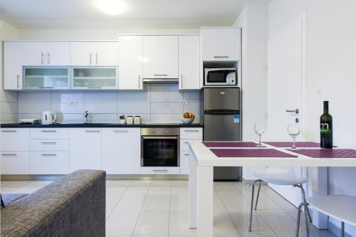una cocina con armarios blancos y una mesa con copas de vino en Apartments Kalelarga, en Zadar