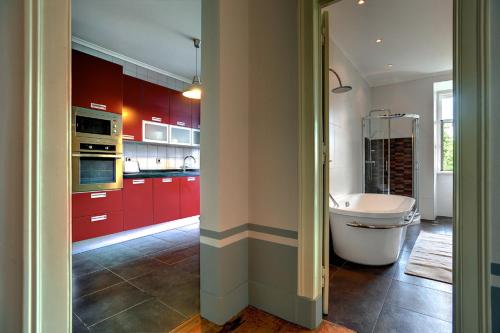 a kitchen with red cabinets and a white tub at Apartments of the Marques in Lisbon
