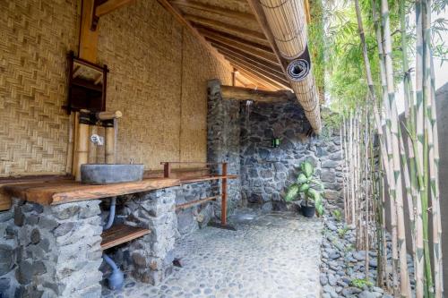 a stone bathroom with a sink and a stone wall at Baha Baha Villas West Sumbawa Yoyos Wellness Center, Gym, Yoga, Skate Park, Bar & Cafe in Sekongkang
