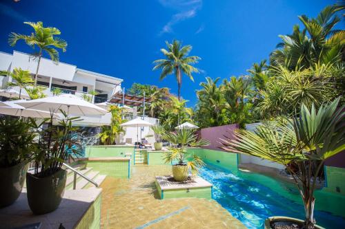 a resort with a pool and palm trees at Port Douglas Peninsula Boutique Hotel - Adults Only Haven in Port Douglas