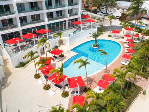 an aerial view of a hotel with a pool and red umbrellas at Boca Beach Residence hotel in Boca Chica