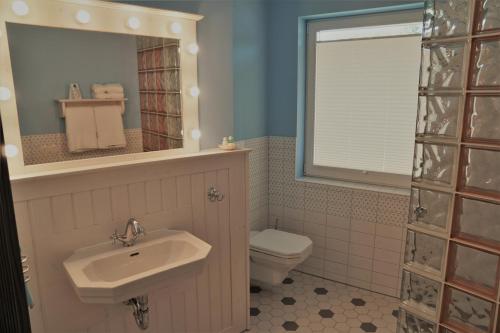 a bathroom with a sink and a toilet and a mirror at Themenhotel 50's Ville Motel in Chemnitz