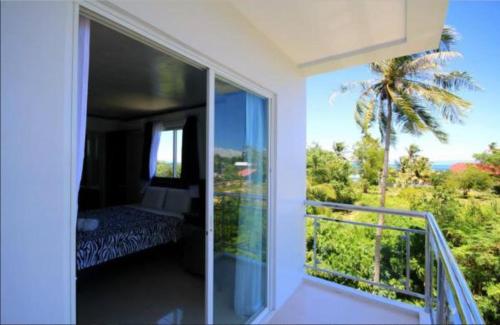 a bedroom with a balcony with a view of a palm tree at Bohol South Beach Hotel in Panglao