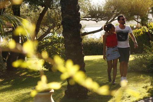 a man and a woman walking through a park at Hotel Club Saraceno - Bovis Hotels in Àrbatax