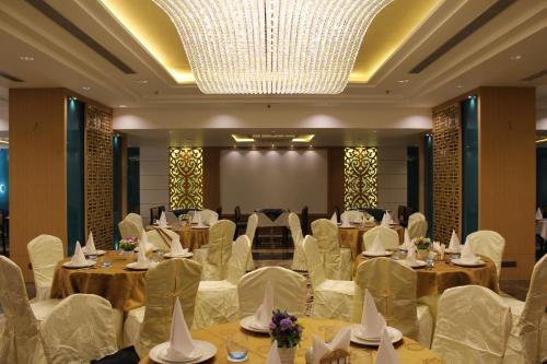 a banquet hall with tables and white chairs and a chandelier at SKK Blu Hotel & Spa in Udaipur